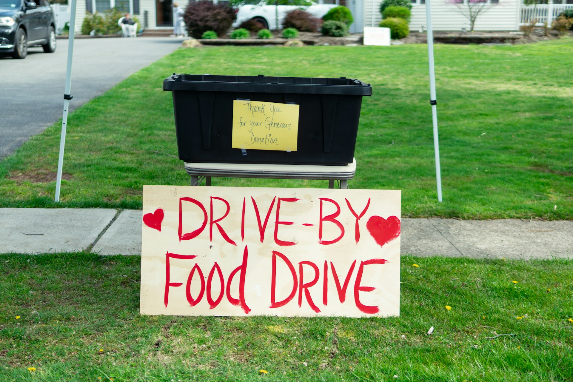 Community food drive donation bin with 'Drive-By Food Drive' sign
